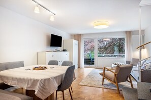 Una sala de estar moderna con comedor, un televisor de pantalla plana montado en la pared, un sofá y una escalera.