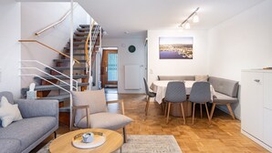 Un salon moderne avec un escalier, un coin repas et une vue sur le paysage urbain.