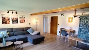 Ein modernes Wohnzimmer mit einem Ecksofa, einem Esstisch mit Stühlen und einer kleinen Bank.