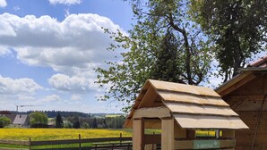 Ein Spielplatz mit einer Rutsche aus Holz und einem Spielhäuschen.