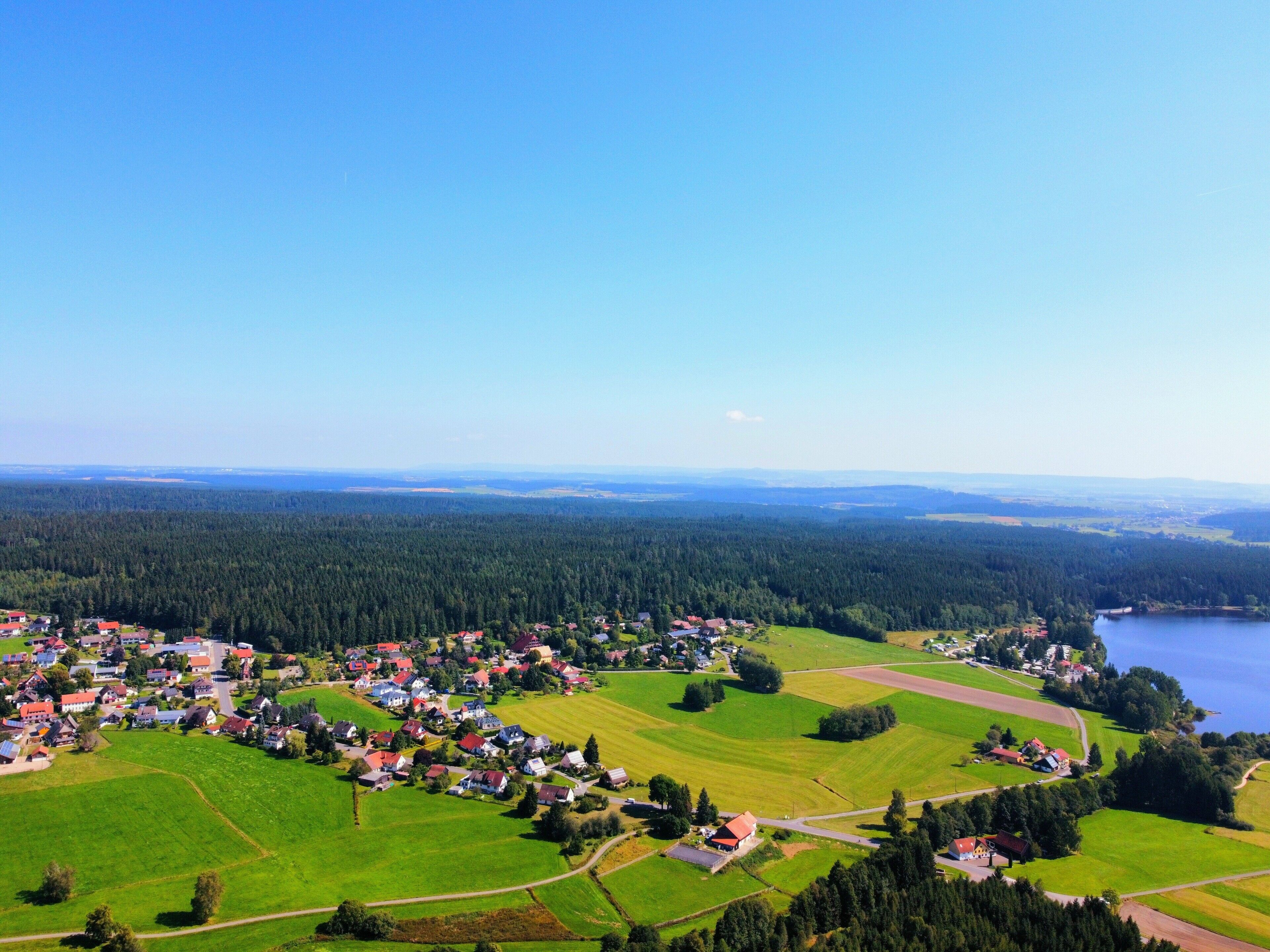 Een landelijk dorp met huizen, velden en een meer.