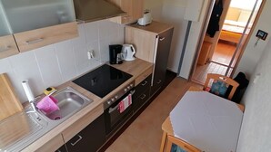 Eine kleine Küche mit Spüle, Herd und Esstisch.