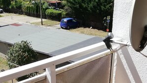 Ein Balkon mit Blick auf ein Wohngebiet, ein blauer Stuhl und ein weißes Geländer.