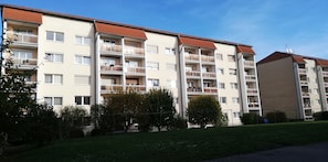 Un immeuble résidentiel à plusieurs étages, doté de balcons, d’un toit plat et surplombant un ciel dégagé.