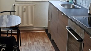 A modern kitchen with wooden cabinets, a stainless steel sink, and a window with purple blinds. - Apartment 'Mücheln 2' with Balcony and Wi-Fi (Mücheln (Geiseltal))