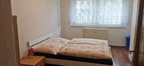 A bedroom with a bed, a nightstand, a window with curtains, and a radiator. - Apartment 'Mücheln 2' with Balcony and Wi-Fi (Mücheln (Geiseltal))