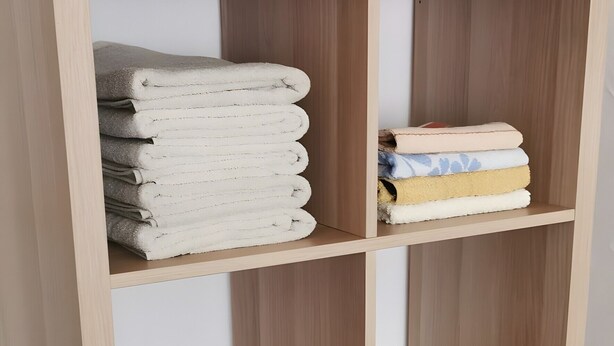 A wooden bookshelf with multiple shelves, some holding folded towels and a blanket. - Apartment 'Mücheln 2' with Balcony and Wi-Fi (Mücheln (Geiseltal))