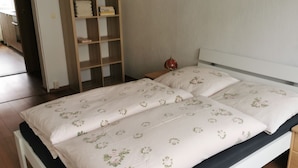 A bed with floral bedding, a bedside table, a nightstand, and a wooden wardrobe. - Apartment 'Mücheln 2' with Balcony and Wi-Fi (Mücheln (Geiseltal))