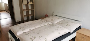 A bed with floral bedding, a bedside table, a nightstand, and a wooden wardrobe. - Apartment 'Mücheln 2' with Balcony and Wi-Fi (Mücheln (Geiseltal))