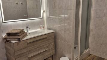 A modern bathroom with a wooden vanity, a large mirror, and a shower enclosure.