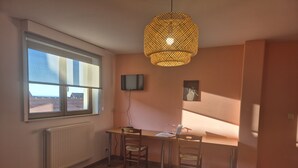 A room with a bed, a desk with a chair, a television, and a large window. - Chambres Thirion (Saint-Hippolyte)