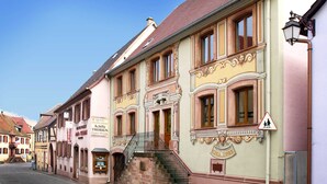 A historic building with a staircase leading to the entrance, a sign indicating a pharmacy, and a pedestrian crossing sign. - Chambres Thirion (Saint-Hippolyte)
