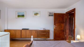 A bedroom with a wooden bed, a nightstand, a wooden dresser, and a door leading to another room.