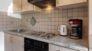 Una cocina con armarios de madera, estufa a gas, cafetera y hervidor.