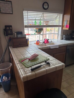 Una cocina con un calendario, un reloj y una ventana con persianas.