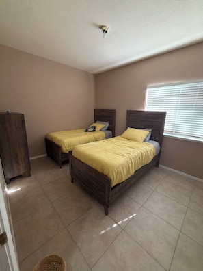 Un dormitorio con dos camas, un armario de madera y una ventana con persianas.