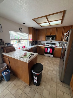 Una cocina con armarios de madera, una isla central, microondas, estufa y refrigerador.