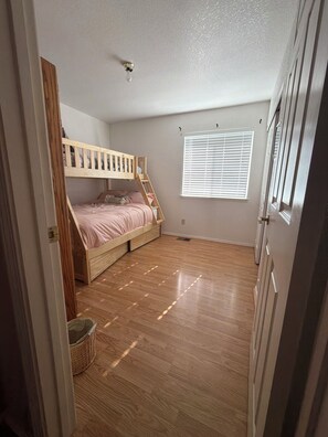 Una habitación con literas, una ventana con persianas y suelo de madera.