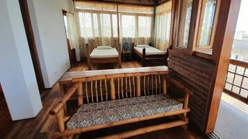 A room with a wooden bench, a small table, and a window with patterned curtains.