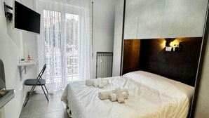 A hotel room with a bed, a chair, a small table, a TV, and a window with curtains. - Confort room with private bath in Rome, Metro C (Roma)