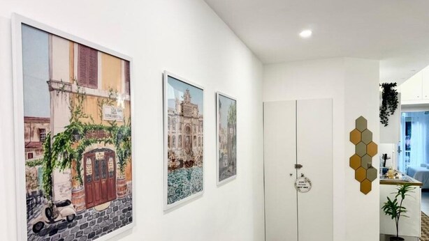 A hallway with three framed artworks depicting architectural scenes, a white door, and a hexagonal wall decoration. - Confort room with private bath in Rome, Metro C (Roma)