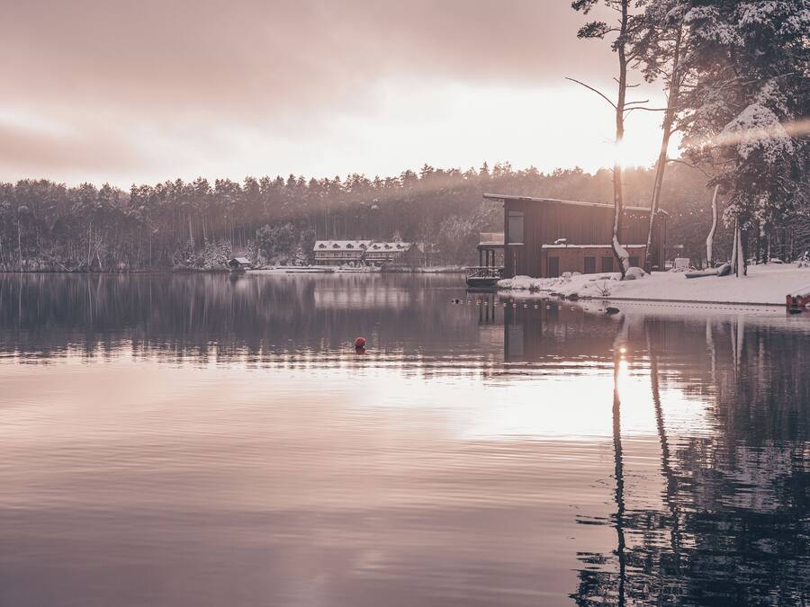 Une propriété paisible au bord d’un lac, avec un chalet moderne, un quai et un paysage enneigé.