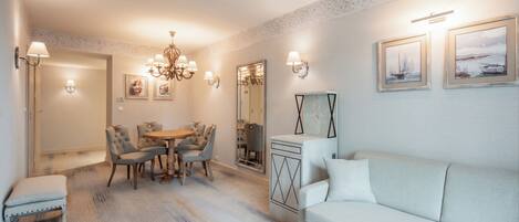 A dining area with a chandelier, a sofa, and a mirror.