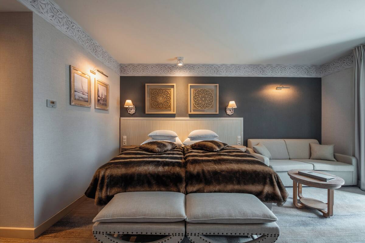 Un dormitorio moderno con una cama grande, un sofá y una mesita de noche.