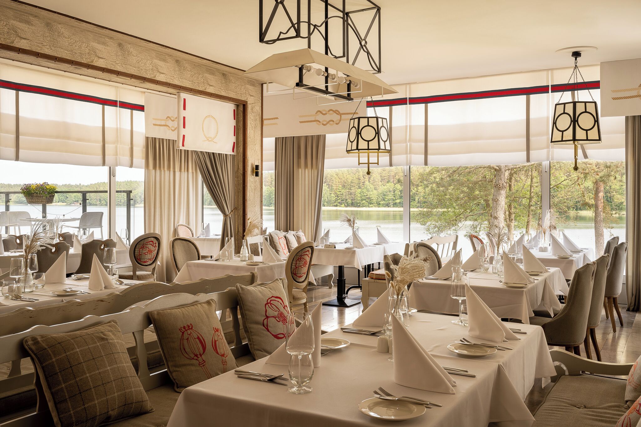 A dining area with tables set for service, large windows with a view, and modern pendant lighting.