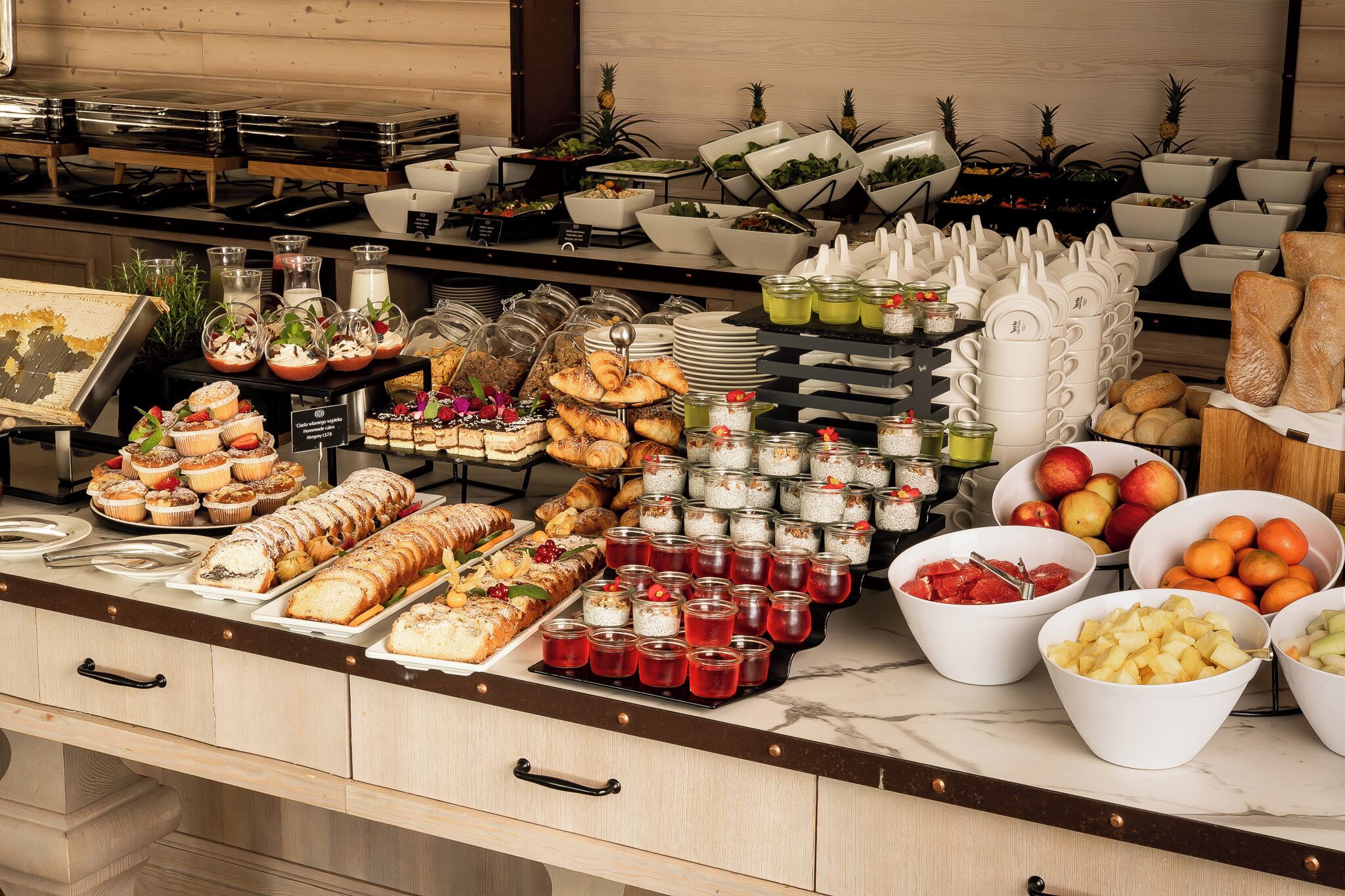 A buffet with various food items, including pastries, fruits, and beverages.