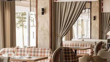 Un comedor con una mesa, sillas y un banco. Hay una ventana con cortinas, una lámpara colgante y una luz empotrada en la pared.