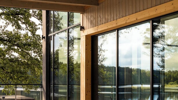 Un moderno espacio de spa con dos jacuzzis, ventanas amplias y vistas a un lago.
