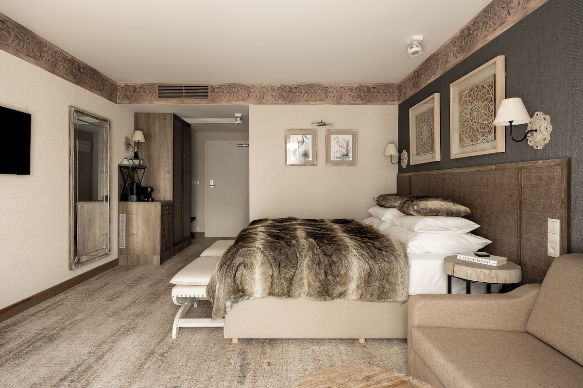 Un dormitorio con cama, sofá, espejo y cuadros en la pared.