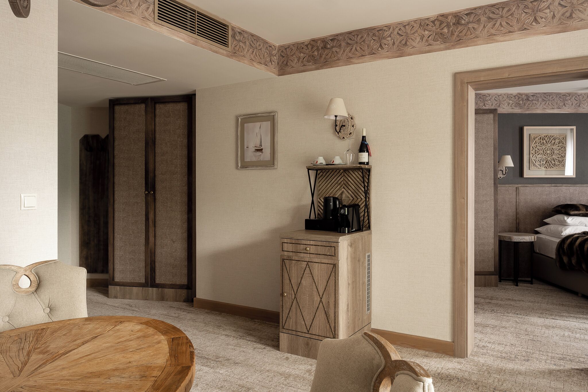 Une chambre d’hôtel avec un lit, une petite table avec une lampe, une armoire et un tableau encadré au mur.