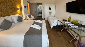 Habitación de hotel con una cama grande, un escritorio con silla, televisión y baño visible a través de una puerta abierta.