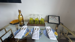 Una mesa dispuesta con platos, servilletas, una botella y vasos, con un cartelón al fondo.