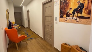 Un pasillo con suelo de madera, una puerta, un cartel y una silla.