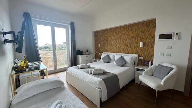 Habitación de hotel moderna con una cama grande, zona de estar y vistas al exterior.