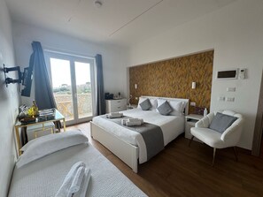 Habitación de hotel moderna con una cama grande, zona de estar y vistas al exterior.