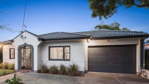 A single-story house with a garage, a front door with a decorative metal gate, and a small front yard. - Bayside Home Away From Home (Brighton)