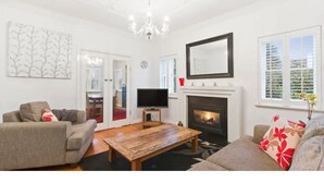 A living room with a fireplace, a television, and a sofa. - Bayside Home Away From Home (Brighton)