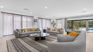 A modern living room with a grey sofa set, a coffee table, and a view of a swimming pool.