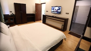 Une chambre d’hôtel avec un grand lit, un téléviseur fixé au mur, une armoire et un bureau avec une chaise.