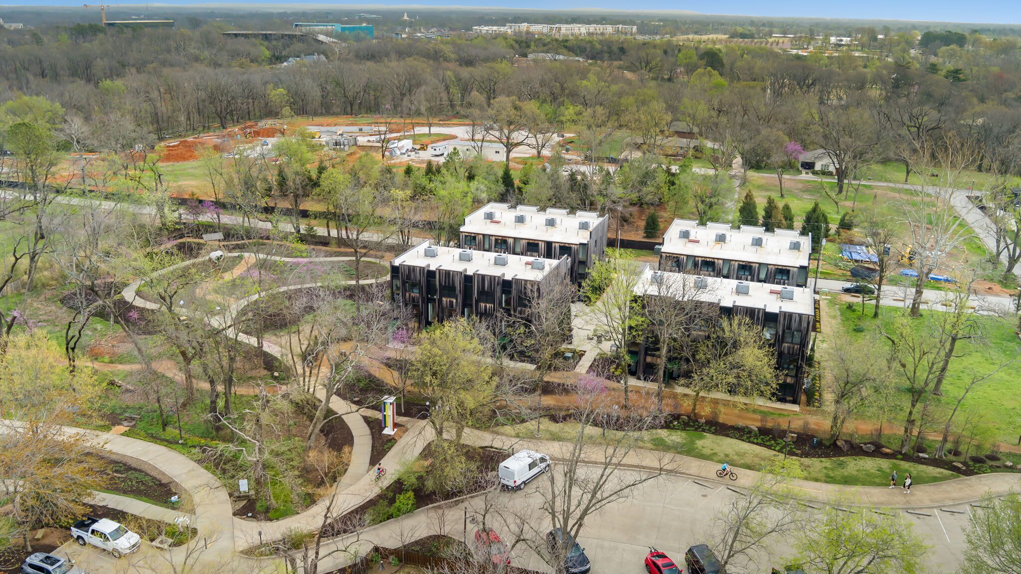 A modern building complex with multiple units, surrounded by landscaped gardens and a parking area.