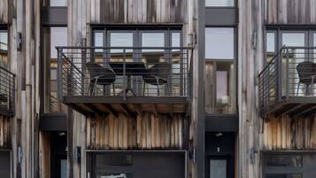 A modern building with a wooden facade, multiple balconies, and a flat roof.