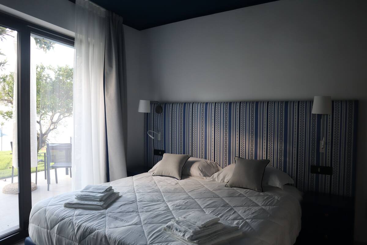 A neatly made bed with pillows and a folded blanket, a bedside lamp, and a patterned headboard.