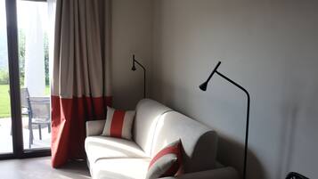 A modern living room with a sofa, two floor lamps, and a sliding glass door leading to an outdoor area.