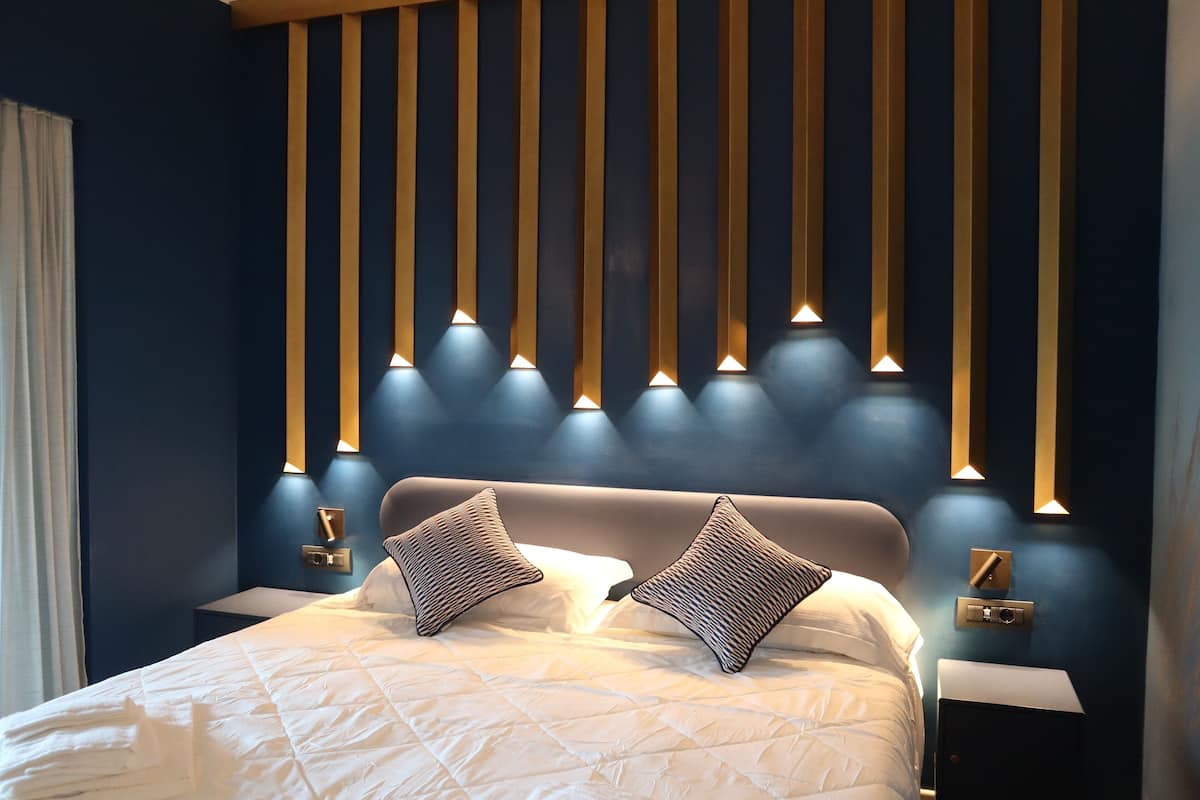 A modern bedroom with a large bed, two bedside tables, and a wall-mounted light fixture.