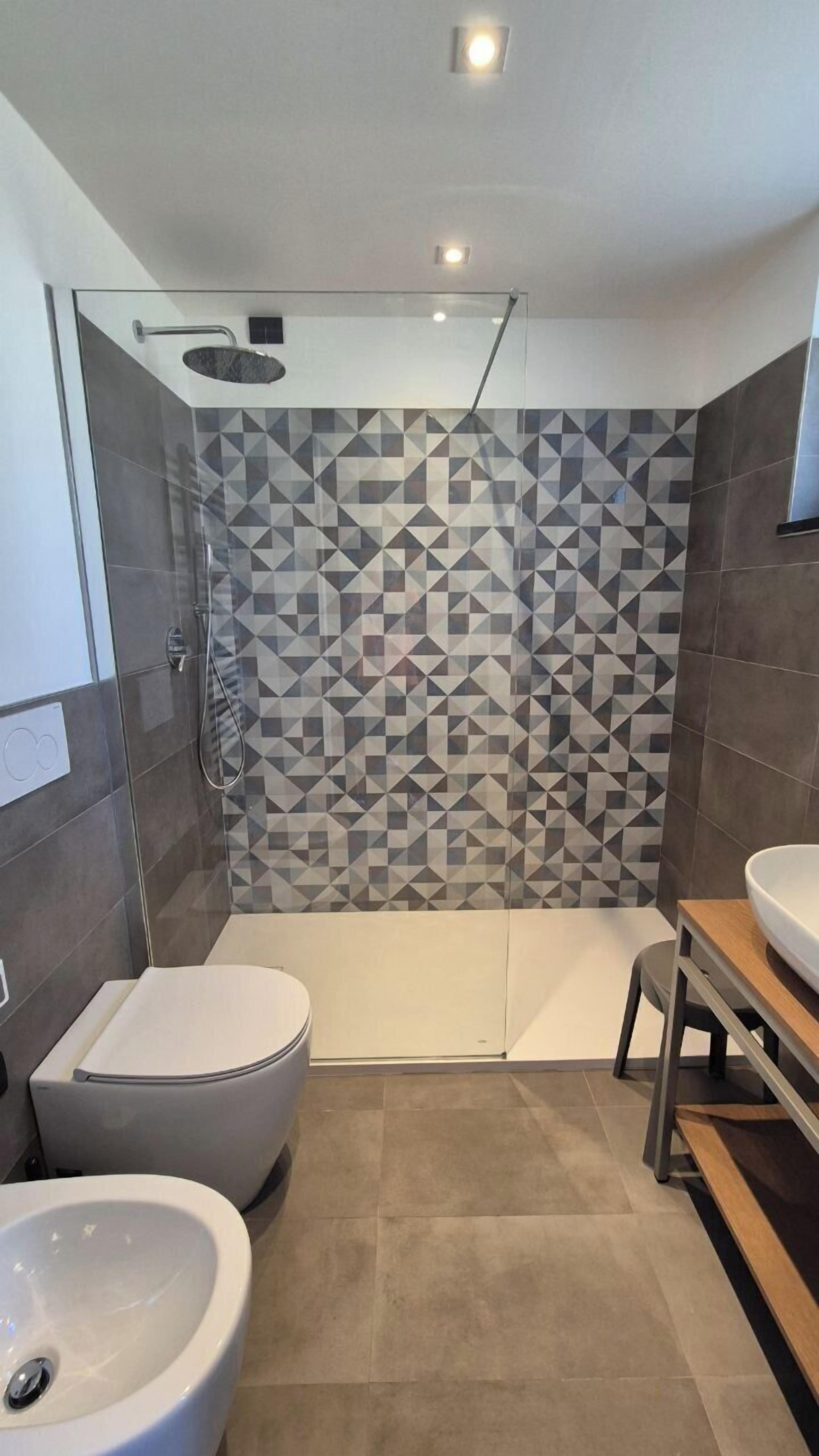 Un baño moderno con ducha de vidrio, un bidé y un tocador con lavabo.