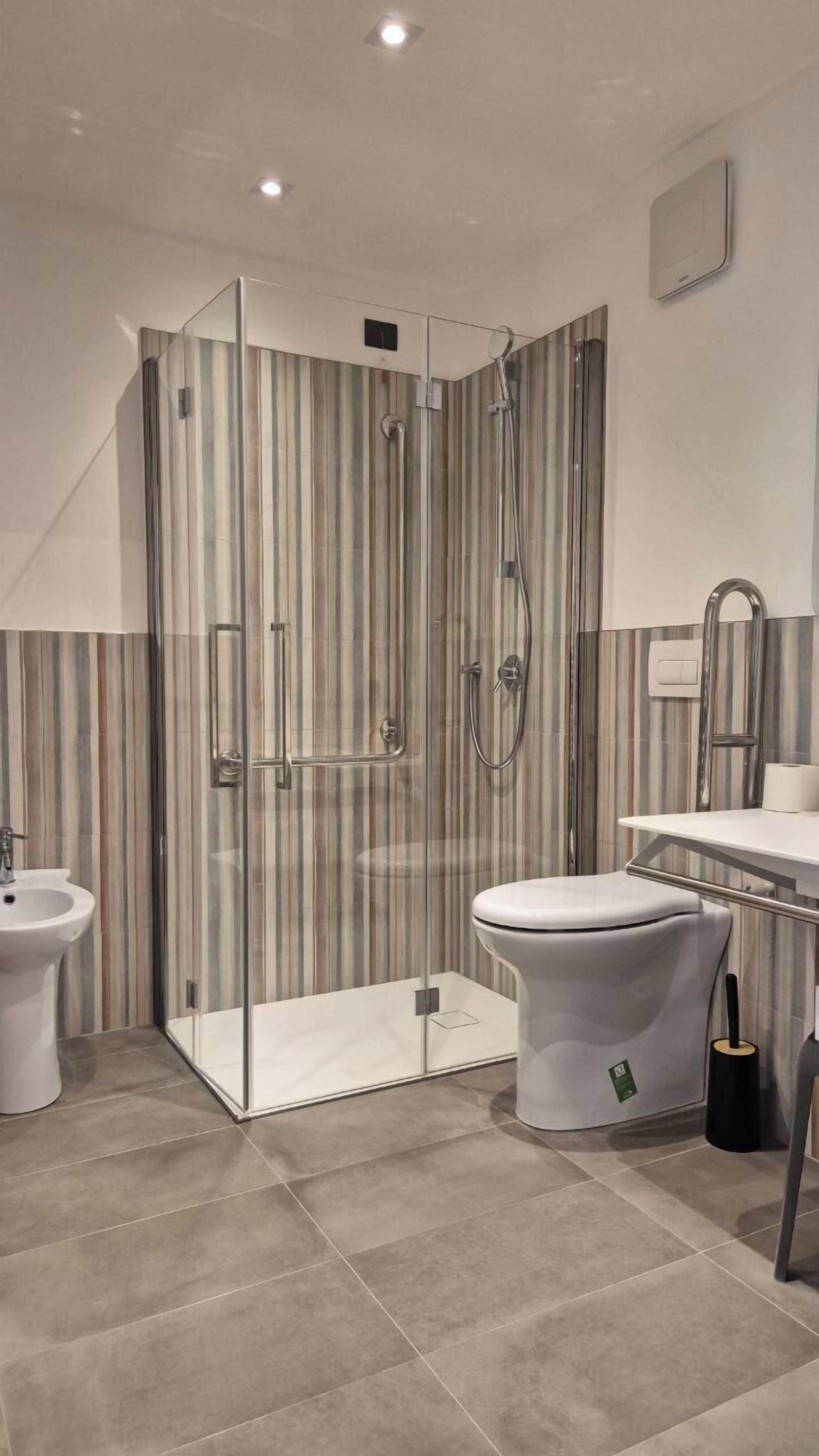 A modern bathroom with a glass-enclosed shower, a bidet, a toilet, and a vanity with a mirror.